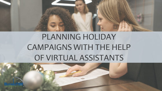 Two women collaborating on holiday campaign planning, with documents on the table and holiday decor in the background. The text overlay reads: 'Planning Holiday Campaigns with the Help of Virtual Assistants.